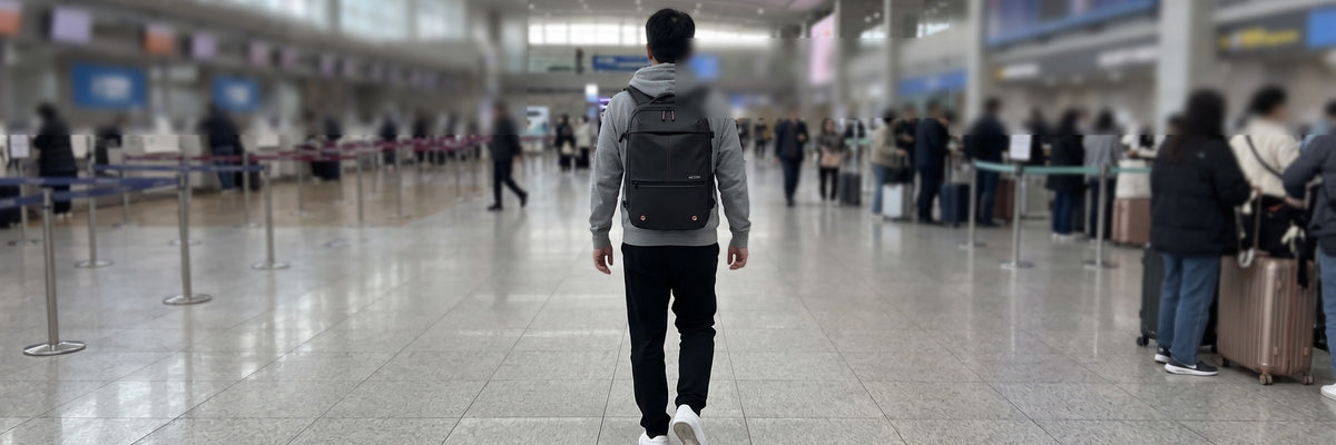 VACKS 백팩을 메고 공항 출국장을 걸어가는 여행자 뒷모습