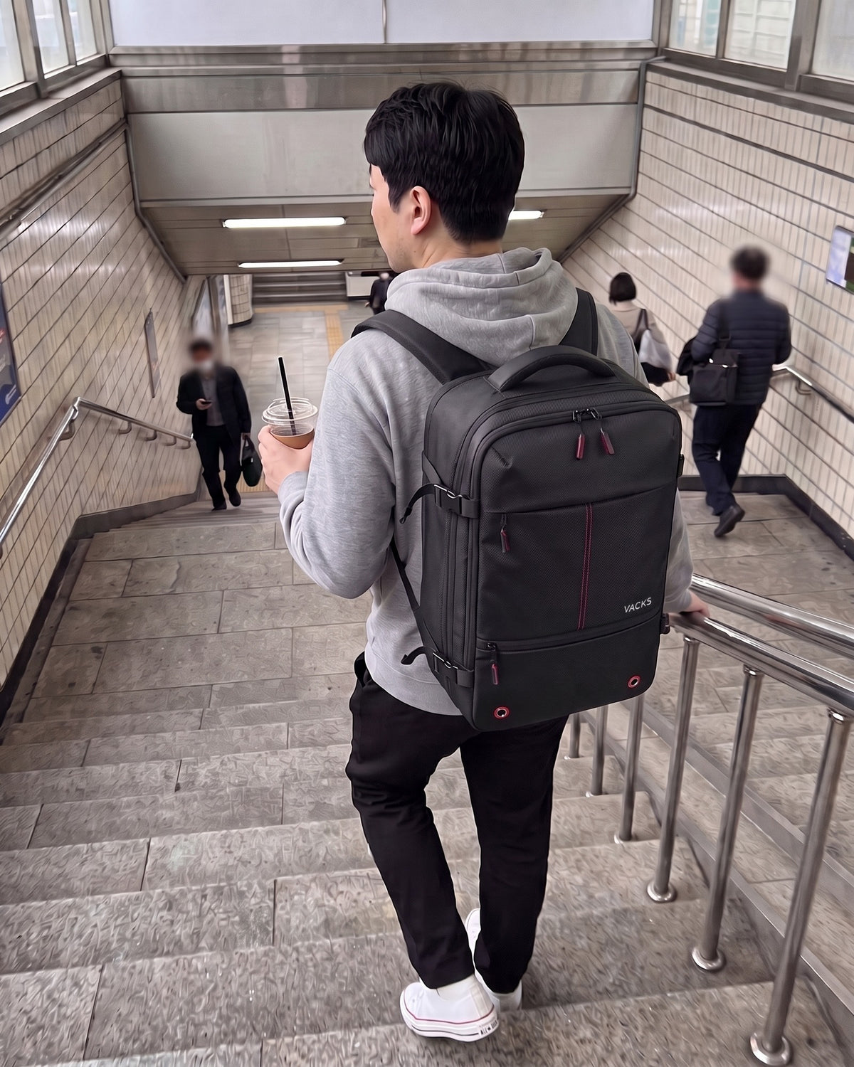 커피를 들고 계단을 내려가는 VACKS 백팩 여행자
